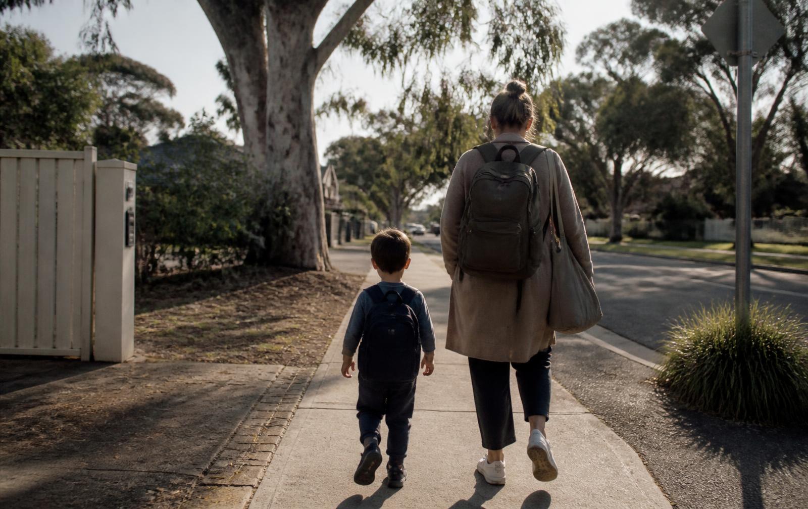 A parent and young child walking together along an Australian suburban street in the morning
